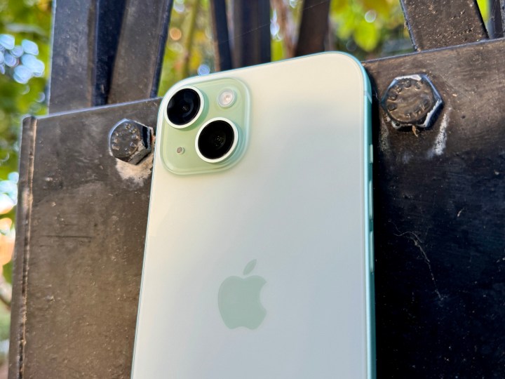 Um iPhone 15 verde mostrando a câmera e a parte traseira em vidro fosco.