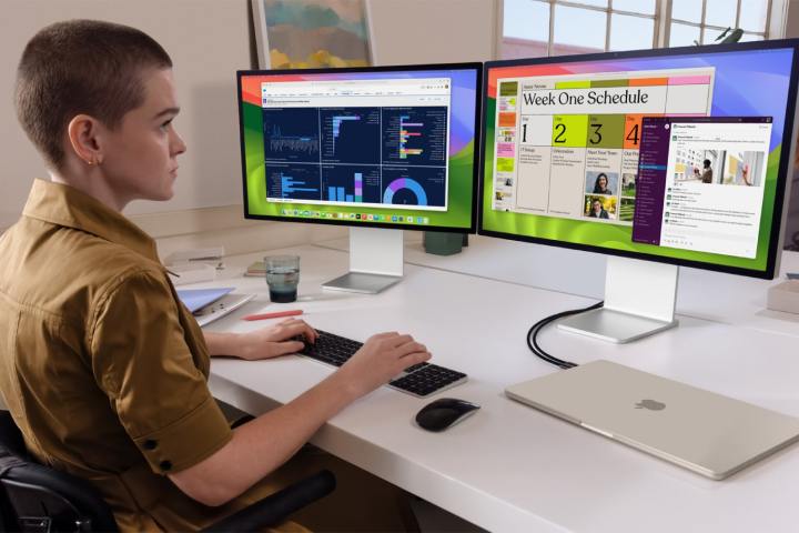 Uma pessoa usando um MacBook Air conectado a dois monitores.