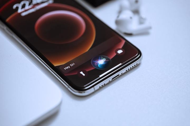Um iPhone em uma mesa com a animação de ativação da Siri sendo reproduzida na tela.