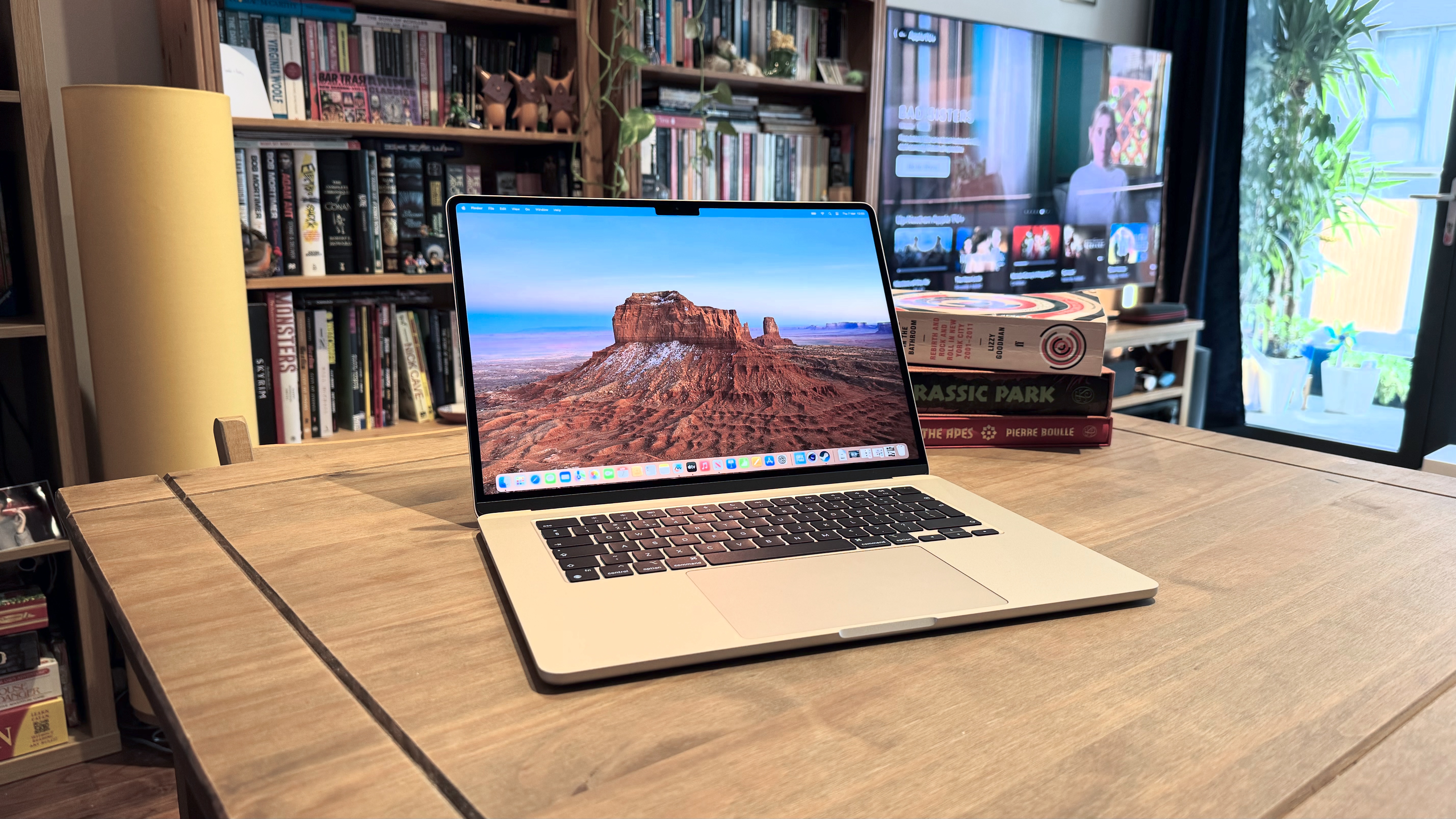 O MacBook Air M3 2024 em uma mesa de madeira em frente a uma estante.